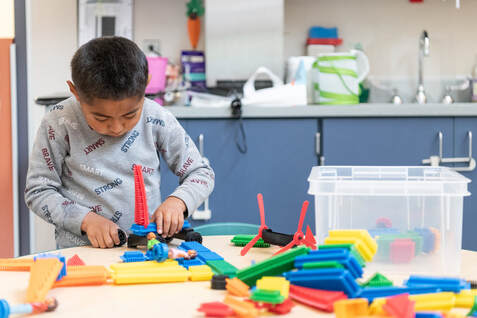 A young boy builds a tower with multi-colored blocks of different shapes and sizes