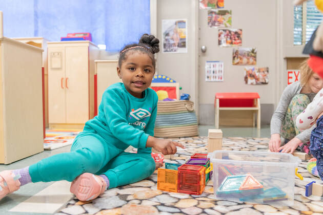 Young girl plays with colorful blocks on the classroom floor